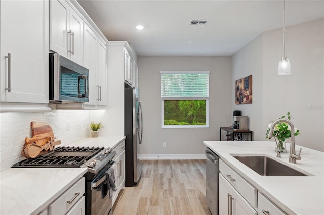 kitchen featuring a sink, tasteful backsplash, white cabinetry, appliances with stainless steel finishes, and light countertops