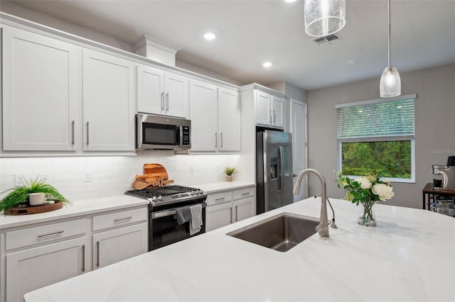 kitchen featuring pendant lighting, a sink, tasteful backsplash, white cabinetry, and stainless steel appliances