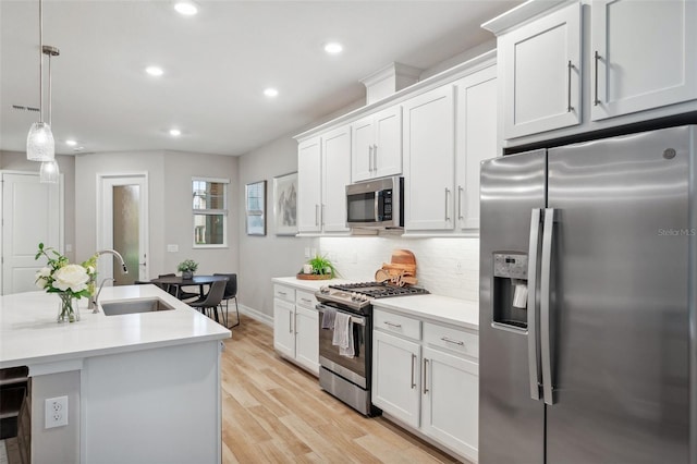 kitchen with light wood-type flooring, light countertops, decorative backsplash, stainless steel appliances, and a sink