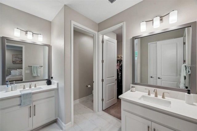 full bath with marble finish floor, two vanities, and a sink