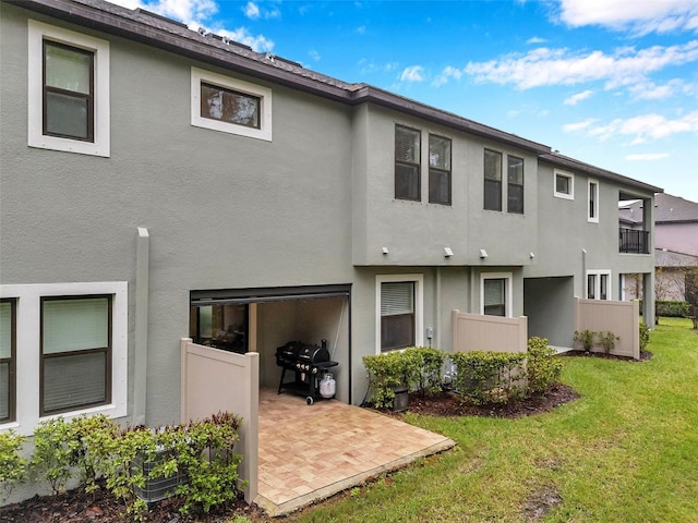 back of property with a patio area, a lawn, and stucco siding