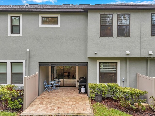 rear view of property with stucco siding, fence, a garage, and a patio area