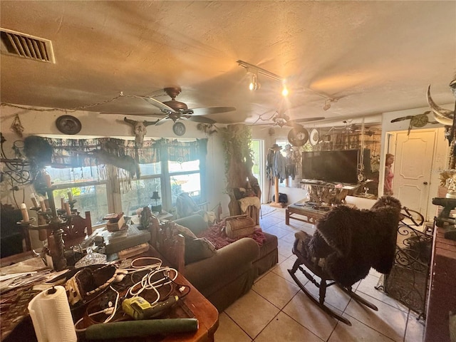 interior space featuring ceiling fan, tile patterned floors, visible vents, and a textured ceiling