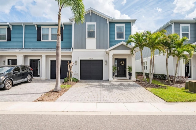 townhome / multi-family property featuring board and batten siding, metal roof, a garage, driveway, and a standing seam roof