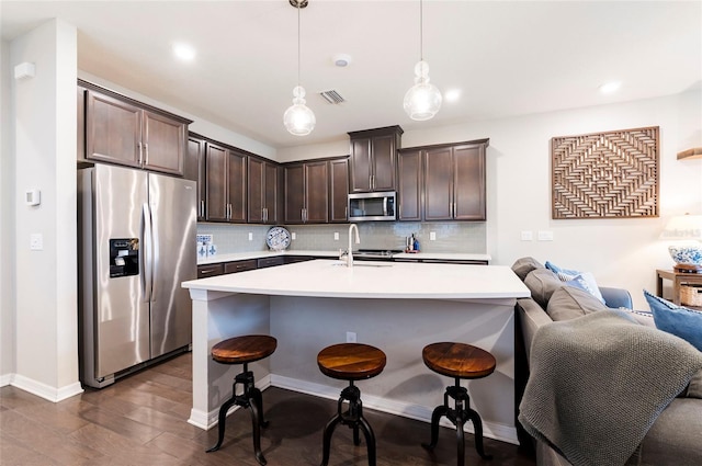 kitchen with tasteful backsplash, dark brown cabinets, stainless steel appliances, and light countertops