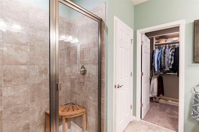 full bathroom featuring a stall shower, a spacious closet, and tile patterned flooring