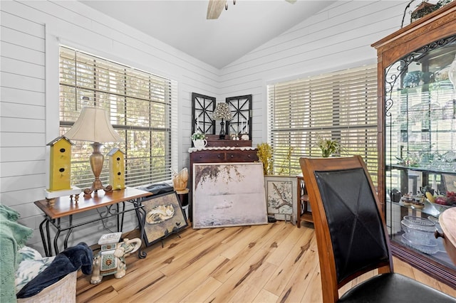 office featuring wood walls, wood finished floors, ceiling fan, and vaulted ceiling