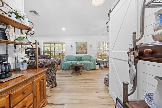 living area with visible vents, light wood-style flooring, and a barn door