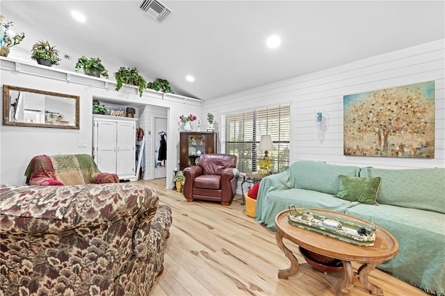 living room with vaulted ceiling, recessed lighting, visible vents, and light wood-type flooring