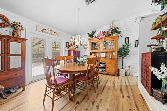 dining area with light wood-type flooring, visible vents, an inviting chandelier, and french doors