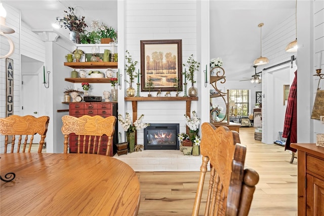 dining area featuring a glass covered fireplace, wood finished floors, and ceiling fan