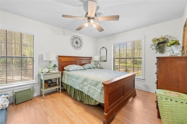 bedroom with baseboards, ceiling fan, radiator heating unit, and light wood finished floors