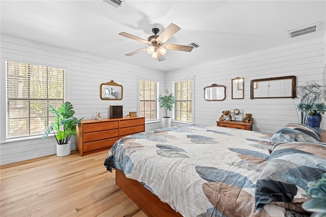 bedroom with light wood finished floors, visible vents, and a ceiling fan