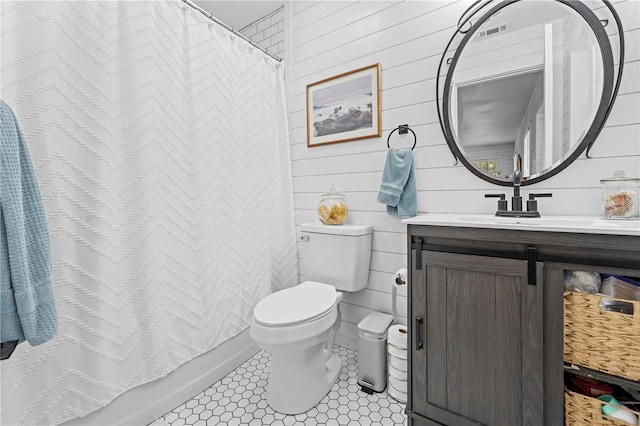 bathroom featuring visible vents, toilet, wooden walls, tile patterned flooring, and vanity