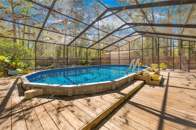 view of swimming pool with a lanai, a fenced in pool, a wooden deck, and a fenced backyard