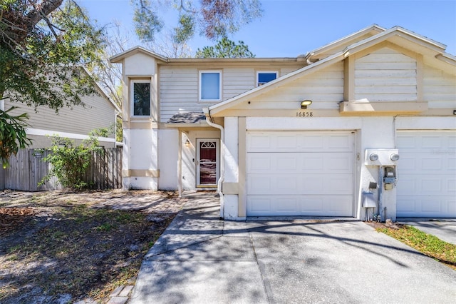 view of front of home featuring stucco siding, an attached garage, concrete driveway, and fence