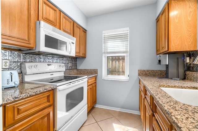 kitchen featuring white appliances, brown cabinetry, tasteful backsplash, and baseboards