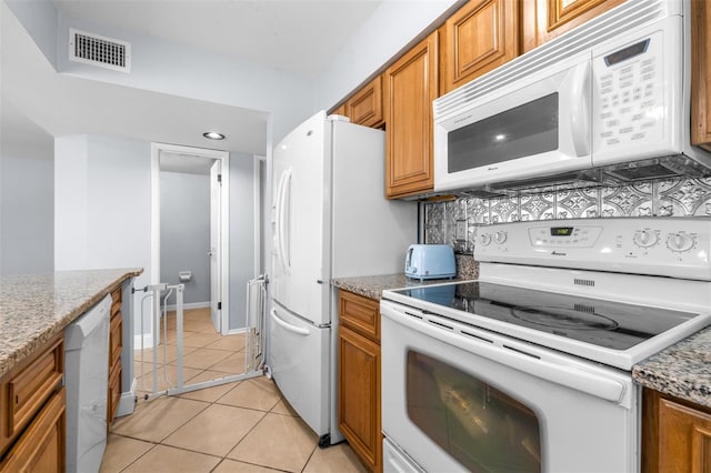 kitchen featuring visible vents, light tile patterned floors, decorative backsplash, brown cabinets, and white appliances