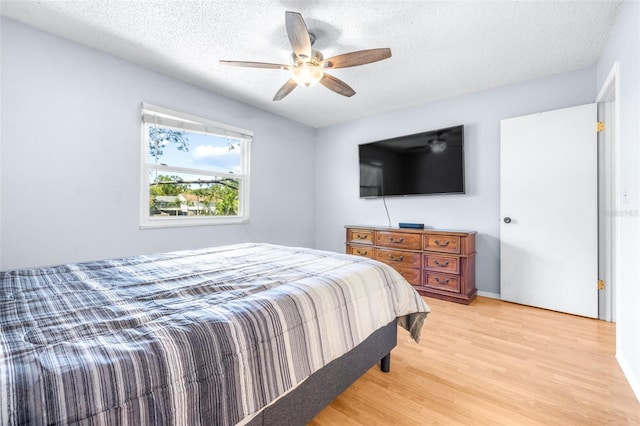 bedroom with a textured ceiling, light wood-style flooring, and a ceiling fan