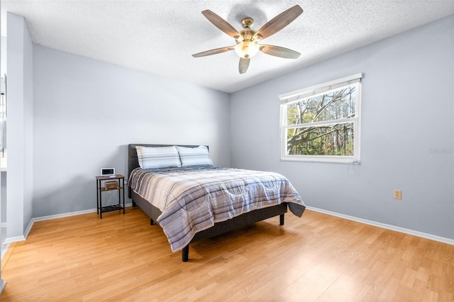 bedroom with a ceiling fan, light wood-style floors, baseboards, and a textured ceiling