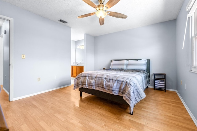 bedroom featuring a ceiling fan, visible vents, baseboards, light wood-style floors, and a textured ceiling