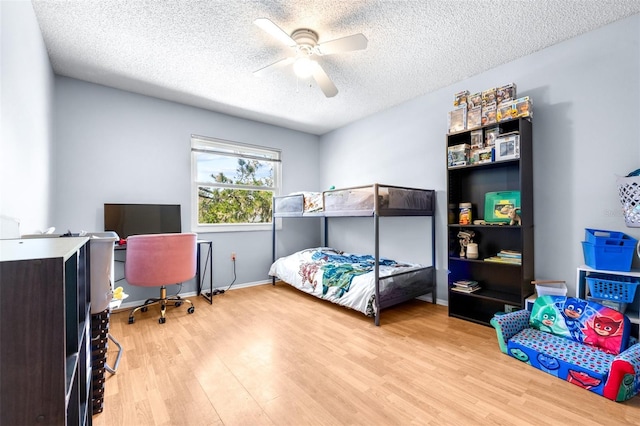 bedroom featuring ceiling fan, baseboards, a textured ceiling, and wood finished floors