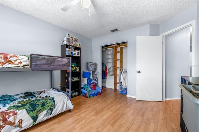 bedroom featuring visible vents, ceiling fan, a closet, a textured ceiling, and light wood-type flooring