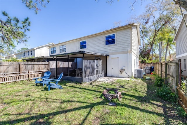 rear view of house with central air condition unit, a lawn, a fenced backyard, and a sunroom