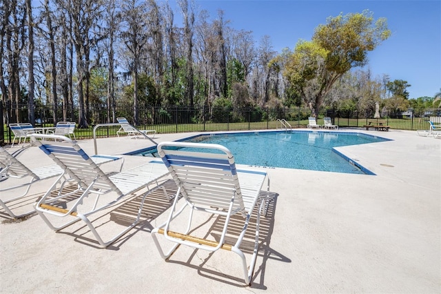 pool with a patio area and fence