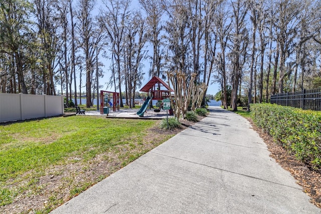 community jungle gym featuring a lawn and fence