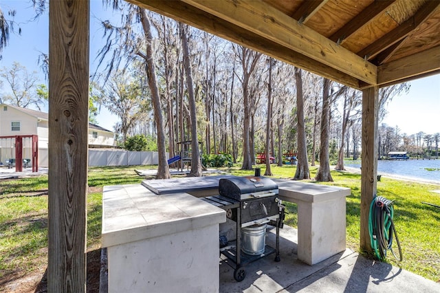 view of patio featuring fence, a water view, and a grill