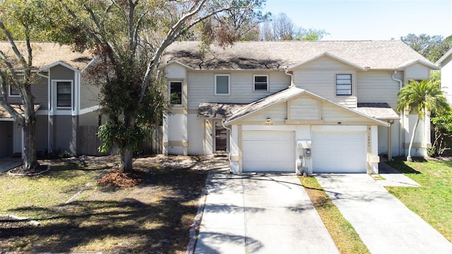 traditional home with driveway, a front yard, a garage, and a shingled roof