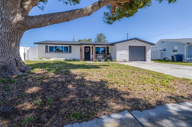 ranch-style house with a front lawn, fence, a garage, and driveway