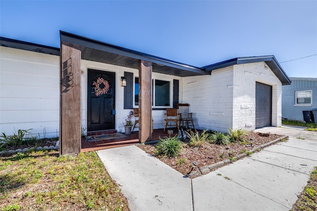 property entrance featuring a garage, covered porch, and concrete driveway