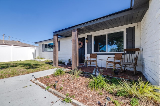 property entrance featuring covered porch and fence