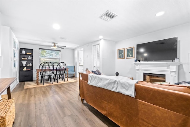 living area with visible vents, ceiling fan, recessed lighting, wood finished floors, and a glass covered fireplace