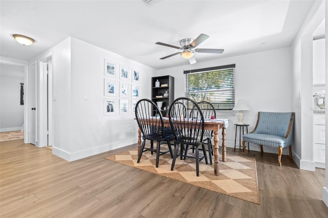 dining space with baseboards, wood finished floors, and a ceiling fan