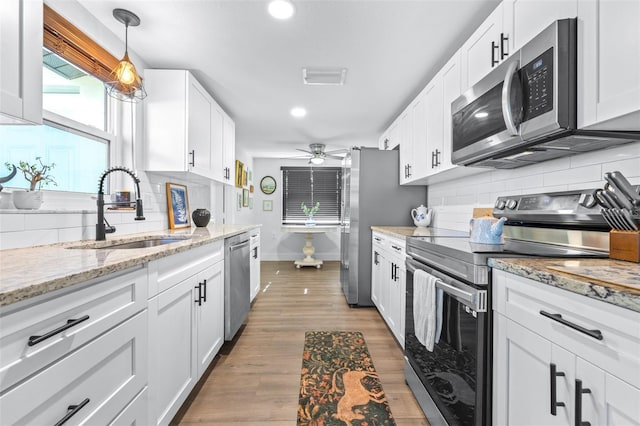 kitchen with visible vents, backsplash, appliances with stainless steel finishes, white cabinetry, and a sink