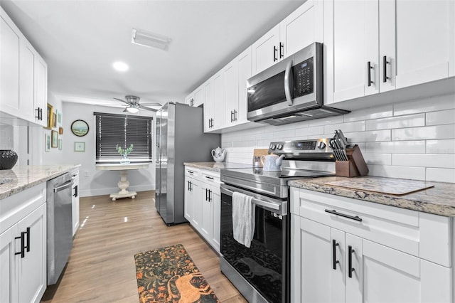 kitchen with visible vents, backsplash, white cabinetry, appliances with stainless steel finishes, and light wood finished floors