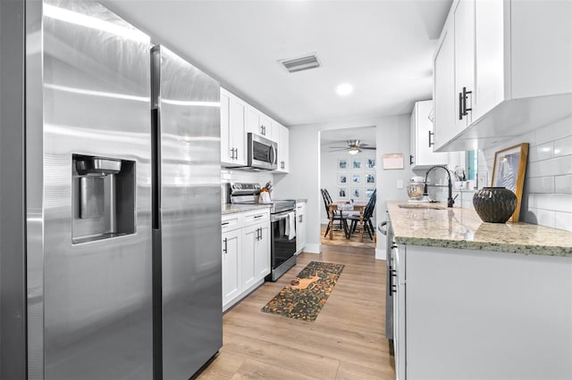 kitchen featuring visible vents, backsplash, light wood-type flooring, stainless steel appliances, and a sink