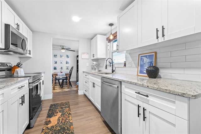 kitchen featuring white cabinetry, stainless steel appliances, light wood-style floors, and a sink