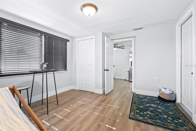 bedroom featuring a closet, visible vents, baseboards, and wood finished floors