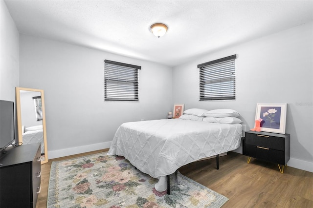 bedroom featuring multiple windows, baseboards, and wood finished floors