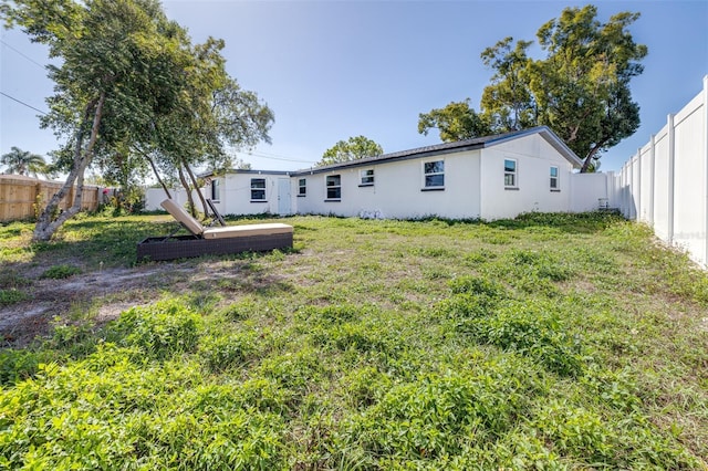 back of property featuring a fenced backyard, a lawn, and stucco siding