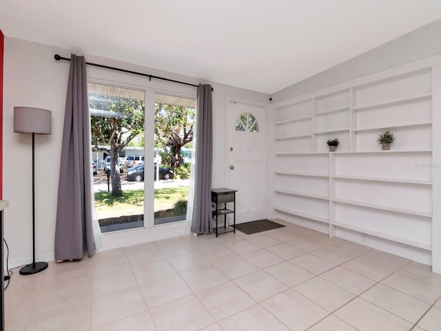 spare room featuring light tile patterned floors and vaulted ceiling