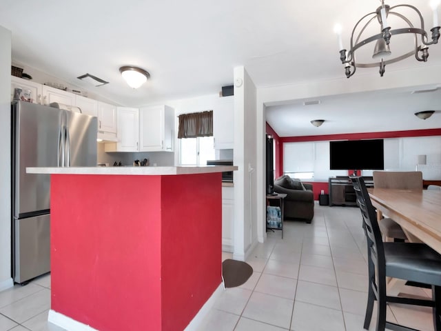 kitchen with white cabinetry, under cabinet range hood, light tile patterned flooring, and freestanding refrigerator