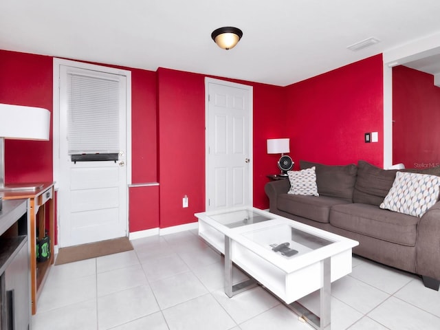 living room featuring an accent wall, light tile patterned floors, baseboards, and visible vents