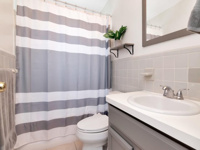 bathroom with a wainscoted wall, toilet, a shower with curtain, tile walls, and vanity