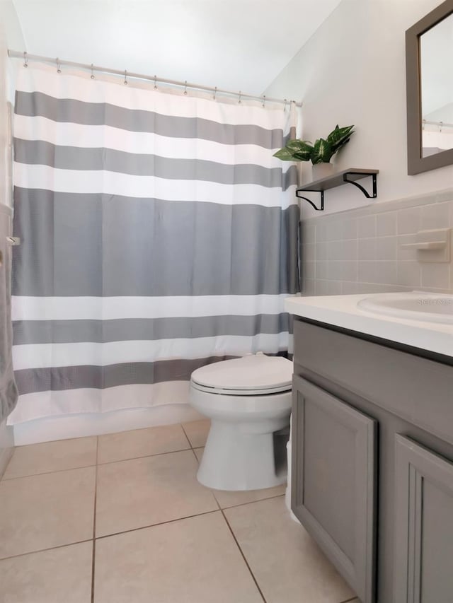 full bathroom with tile patterned flooring, tile walls, toilet, a shower with shower curtain, and vanity