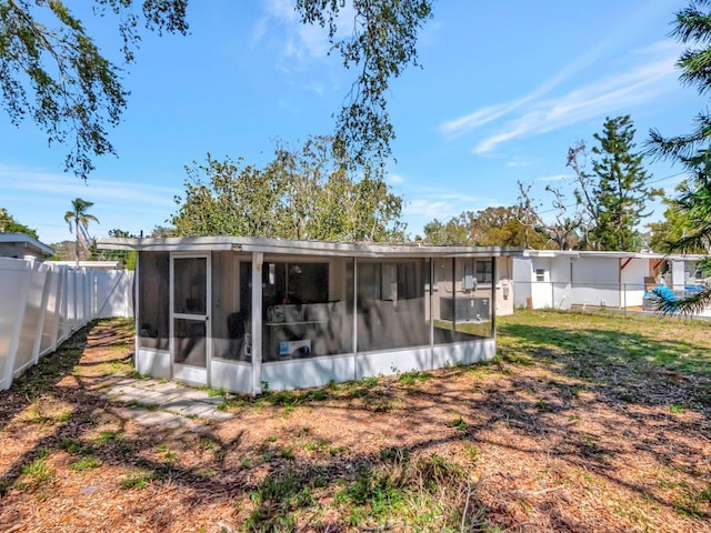 rear view of house with fence and a sunroom